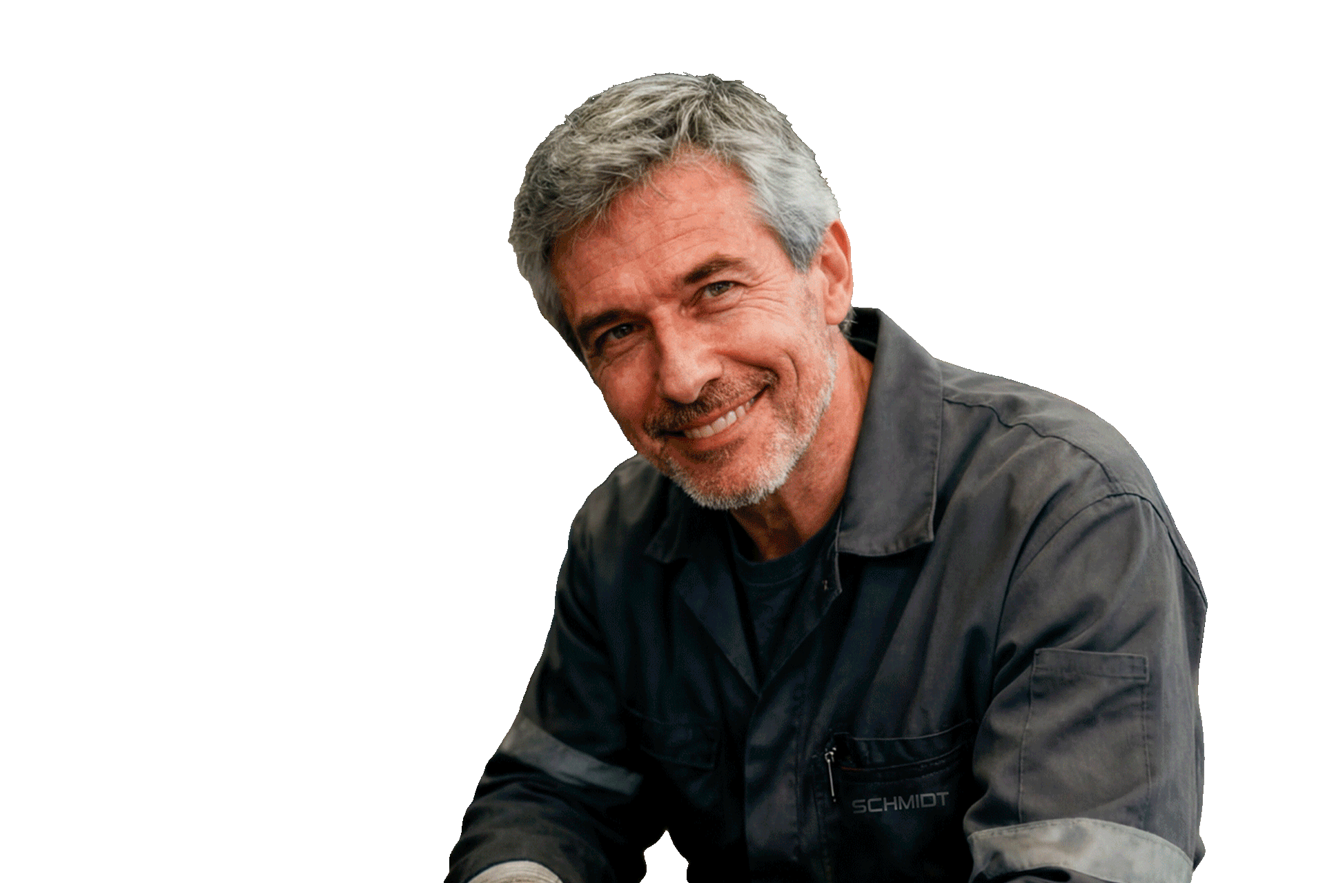 Älterer Mann in grauer Arbeitsjacke sitzt leicht nach vorn gebeugt und blickt freundlich in die Kamera.