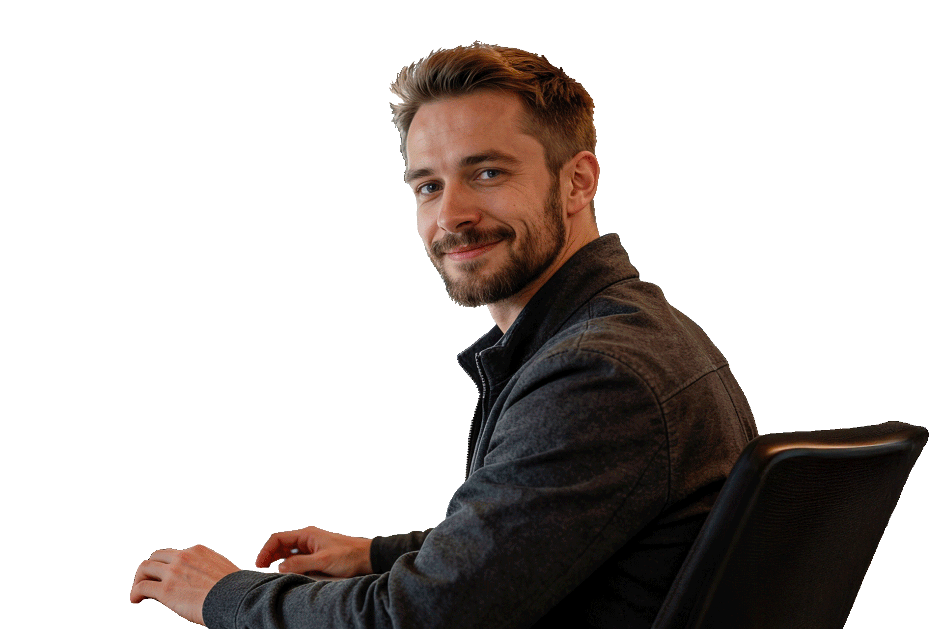 H.M. Schmidt Mitarbeiter sitzt seitlich an einem Tisch, dreht sich zur Kamera und lächelt.